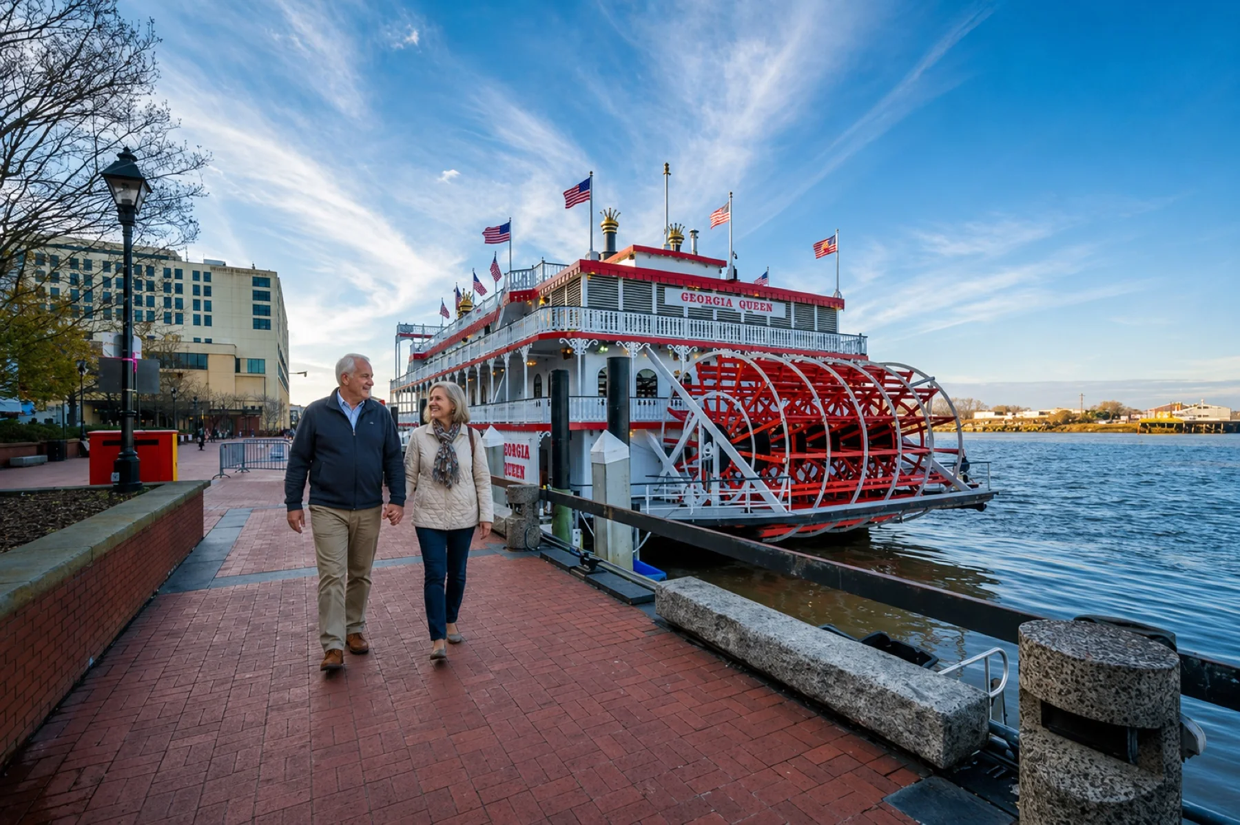 An older couple walking past a paddlewheel riverboat on the riverfront in Savannah, Georgia